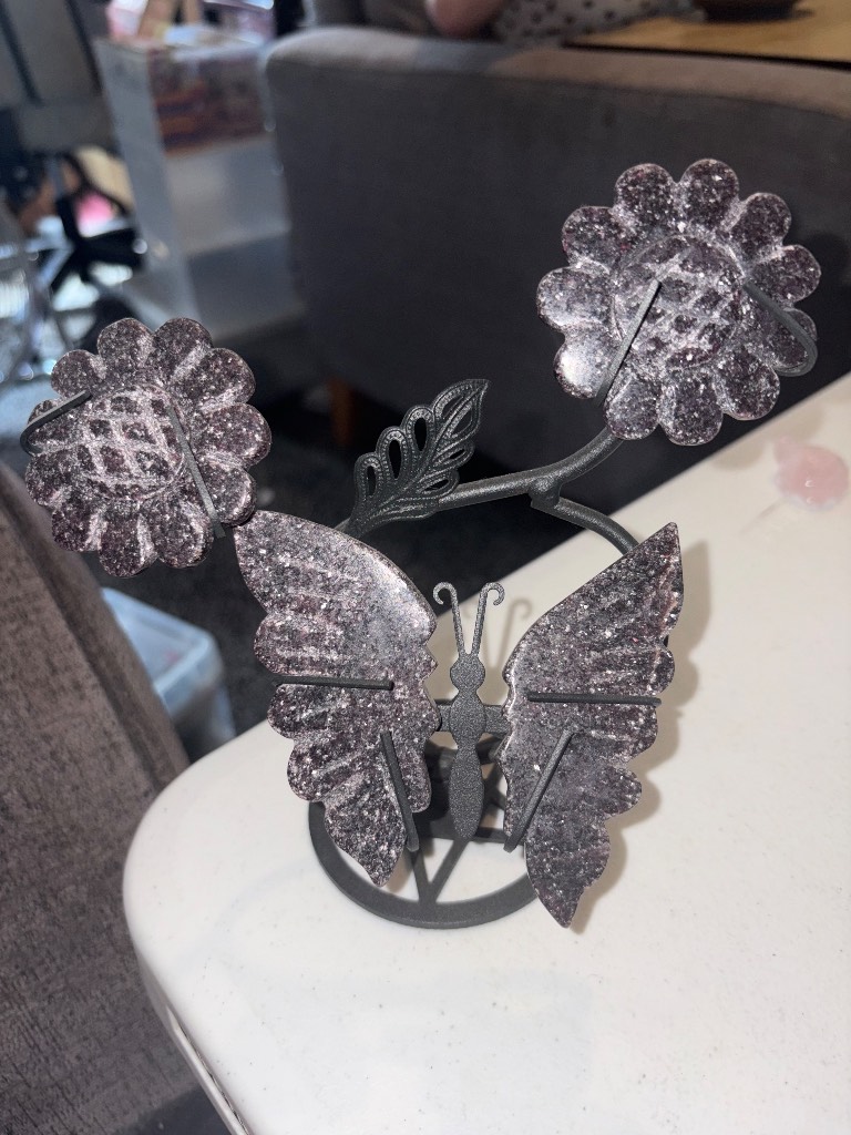 Purple Mica wings with flowers on a black stand