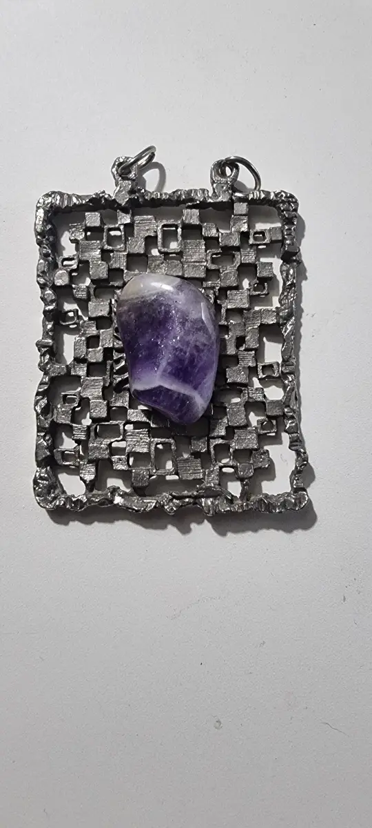Large silver colour pendant with semi precious gemstone in the middle.