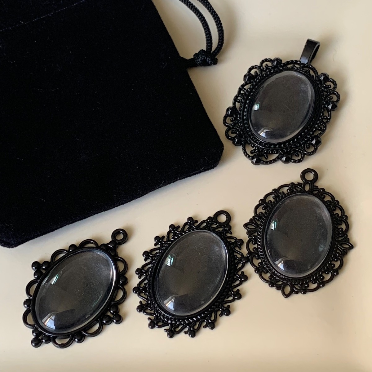 4 oval black filigree pendants with glass cabochons in gift bag