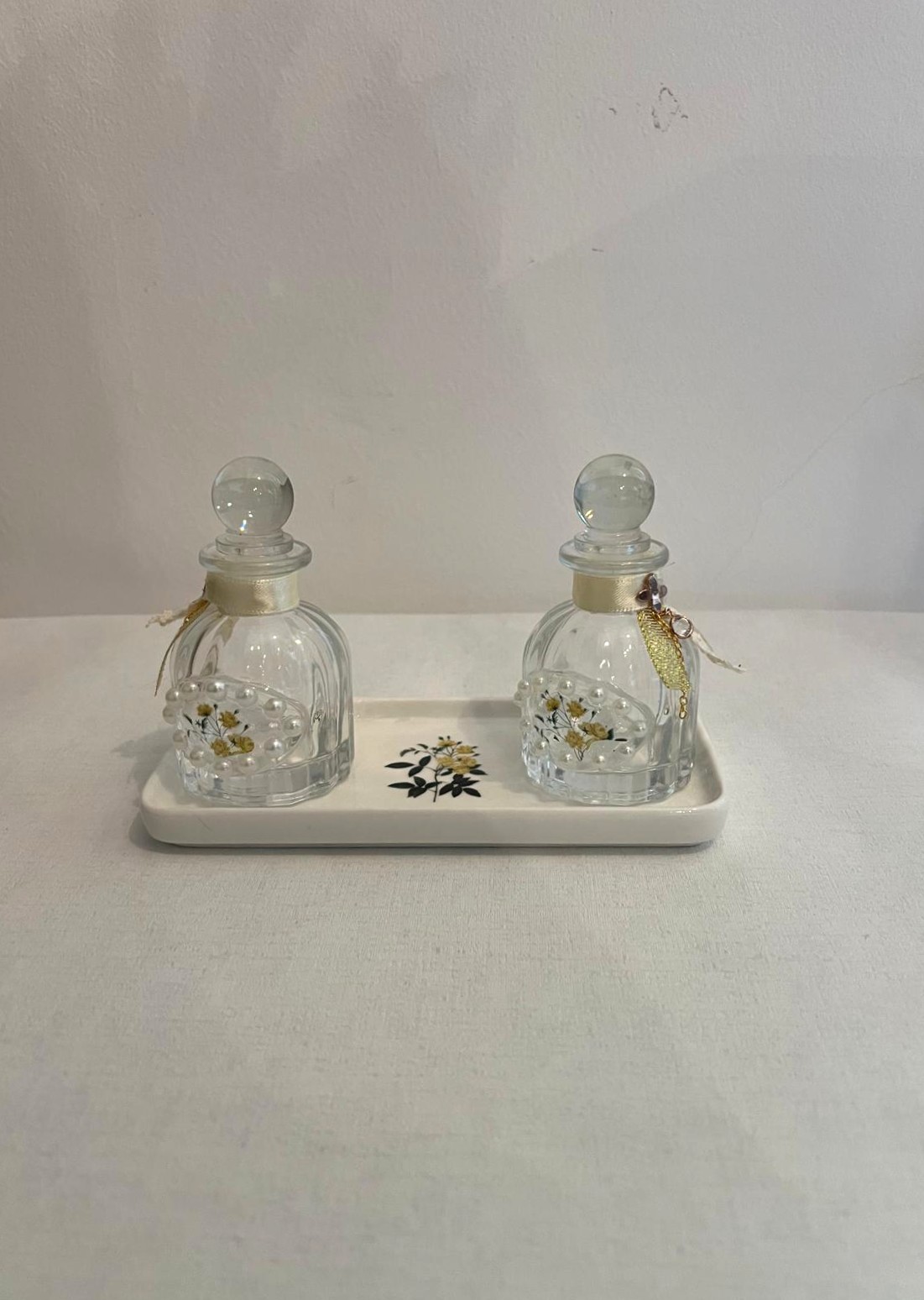 Two Ribbed Floral Perfume Bottles Sitting on a Matching Ivory Rectangular Tray