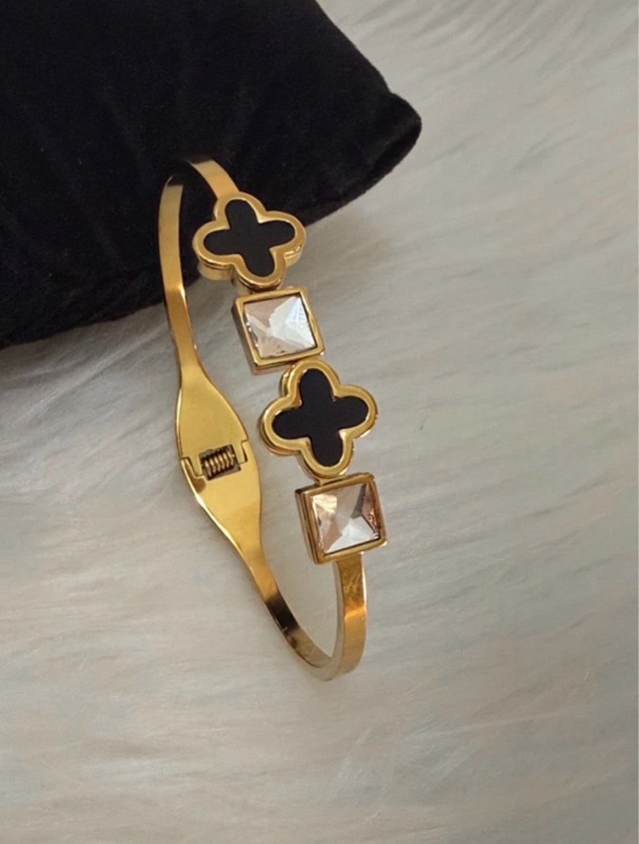 Gold tone bracelet with black clover detail