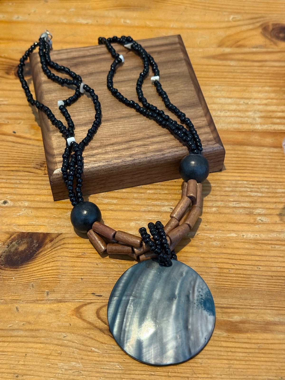 multi strand seed beaded necklace wrapped around a shell pendant