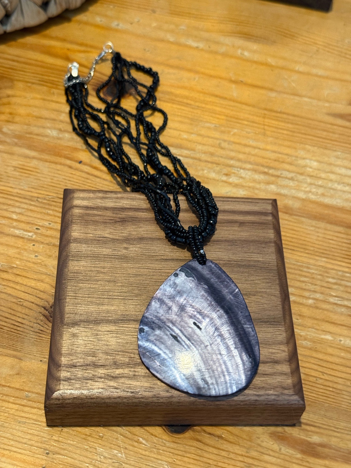 multi strand seed beaded necklace with a silver blue shell pendant