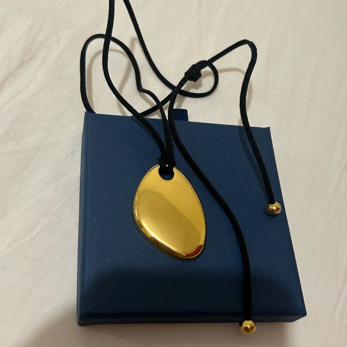 Black cord gold pendant
