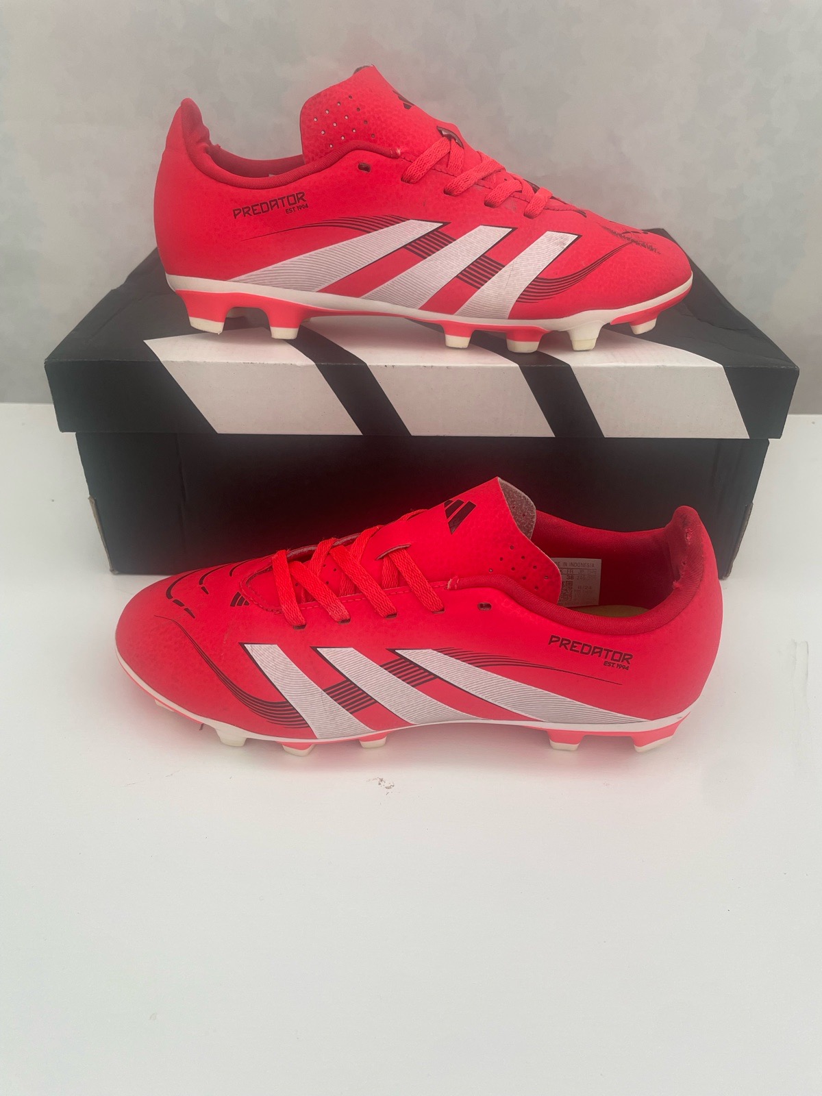 Adidas Predator League football boots are featured in a vibrant Lucid Red colorway