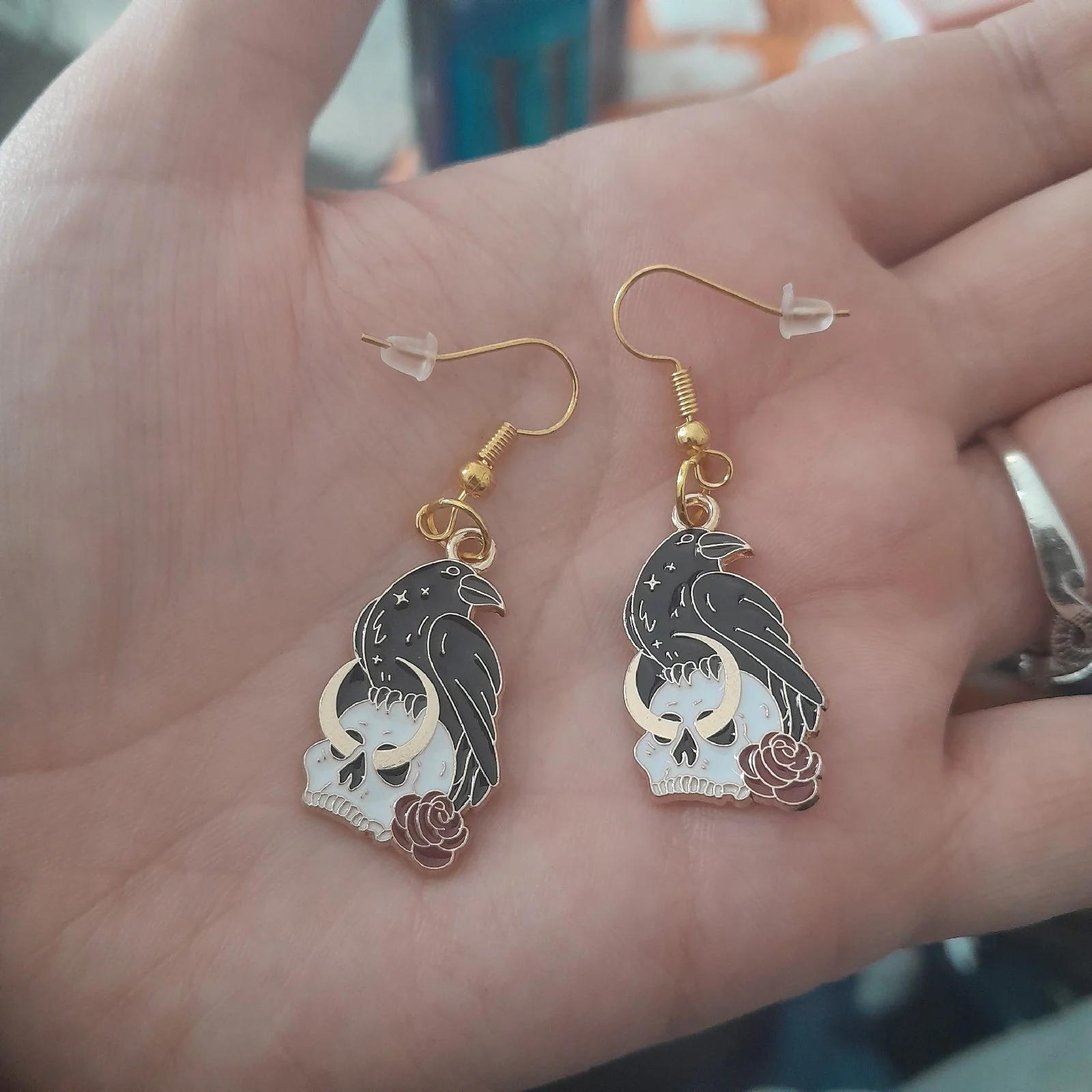Gold hook raven sitting on skull earrings