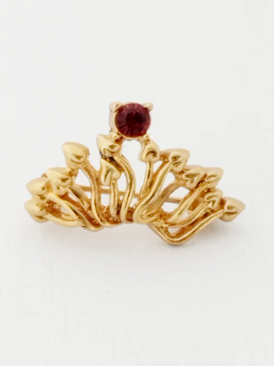 Gold tone brooch with red gem