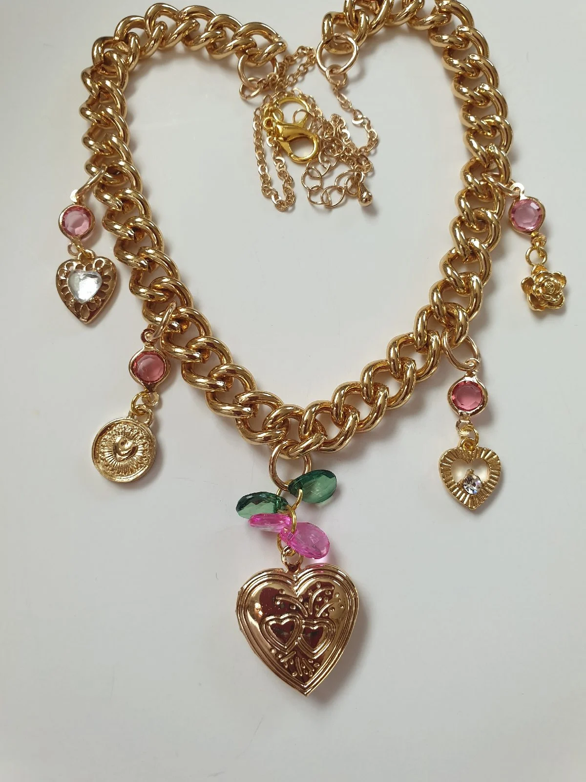 Embossed heart locket necklace surrounded by pink charms