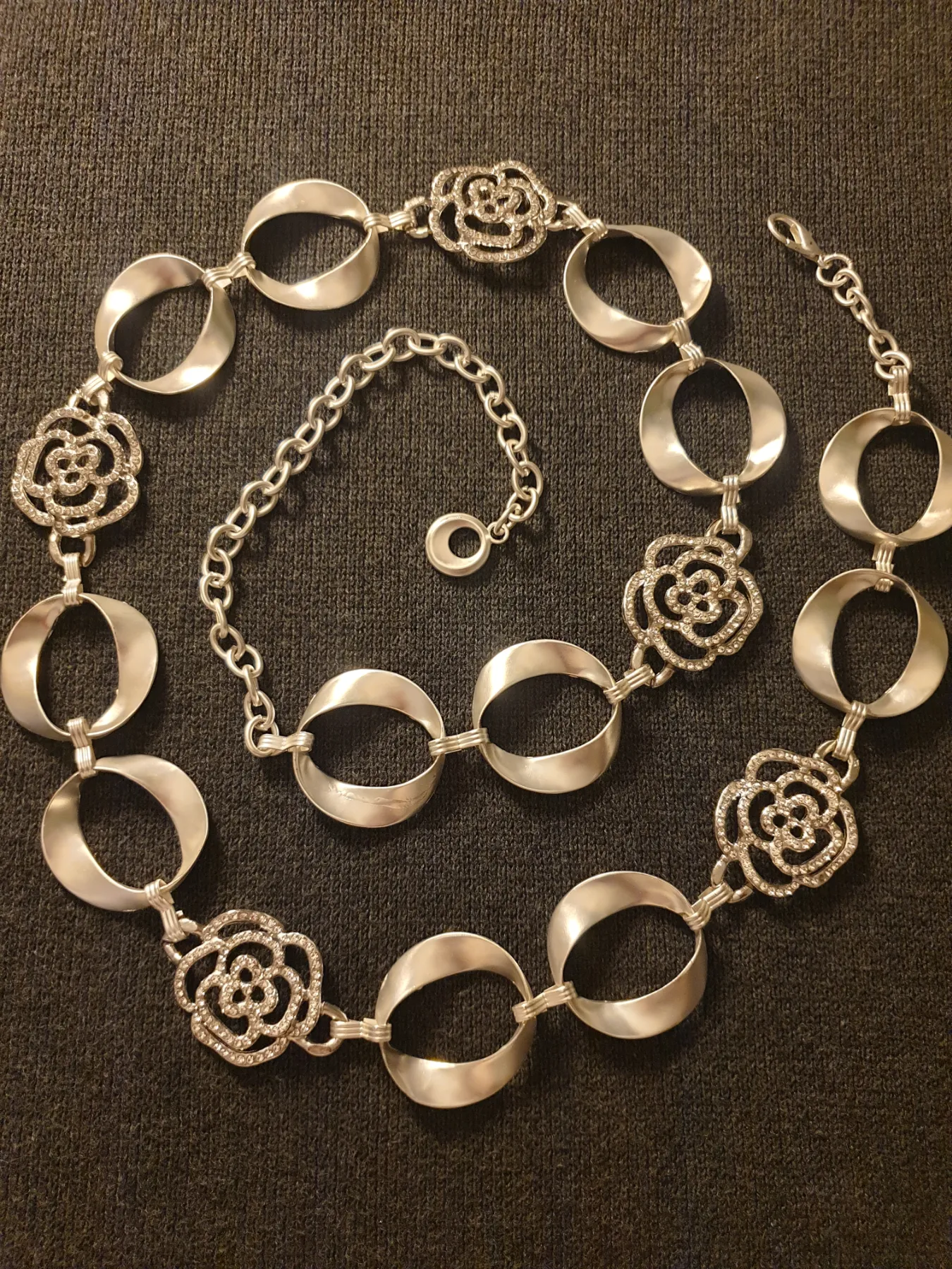 Silver-tone adjustable chain belt with circular links and floral charms. New.  length 119cm