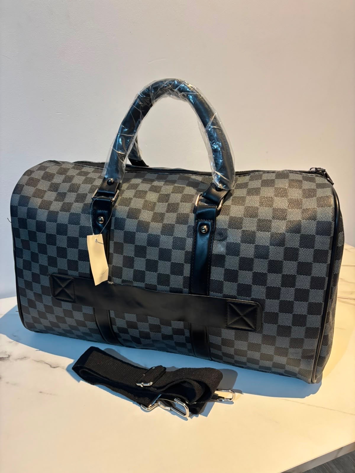 Black & grey checkered travel duffel bag with shoulder strap