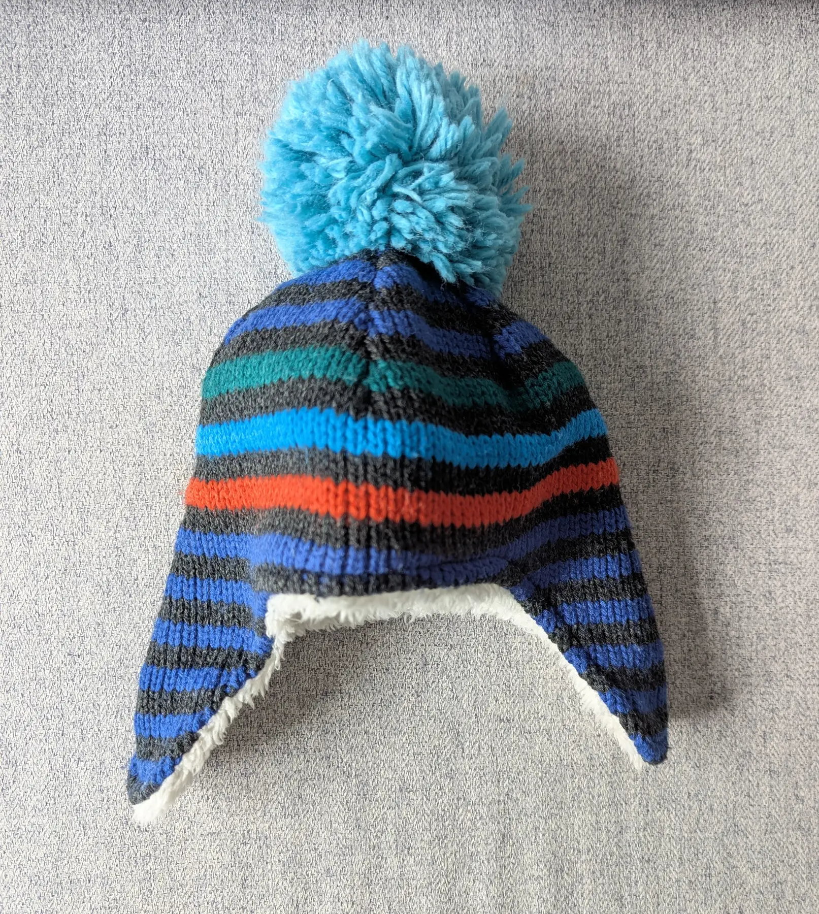 Baby boy blue stripey pom-pom hat with ear warmers, age 0-6 months.