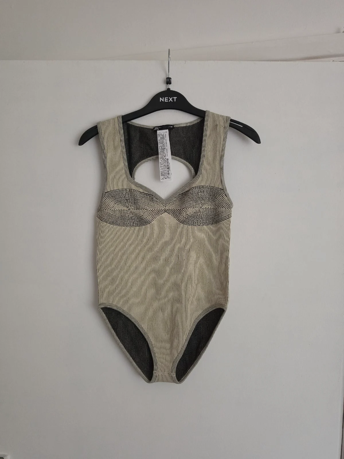 Beige and black ribbed bodysuit with corset-style detailing at the front.