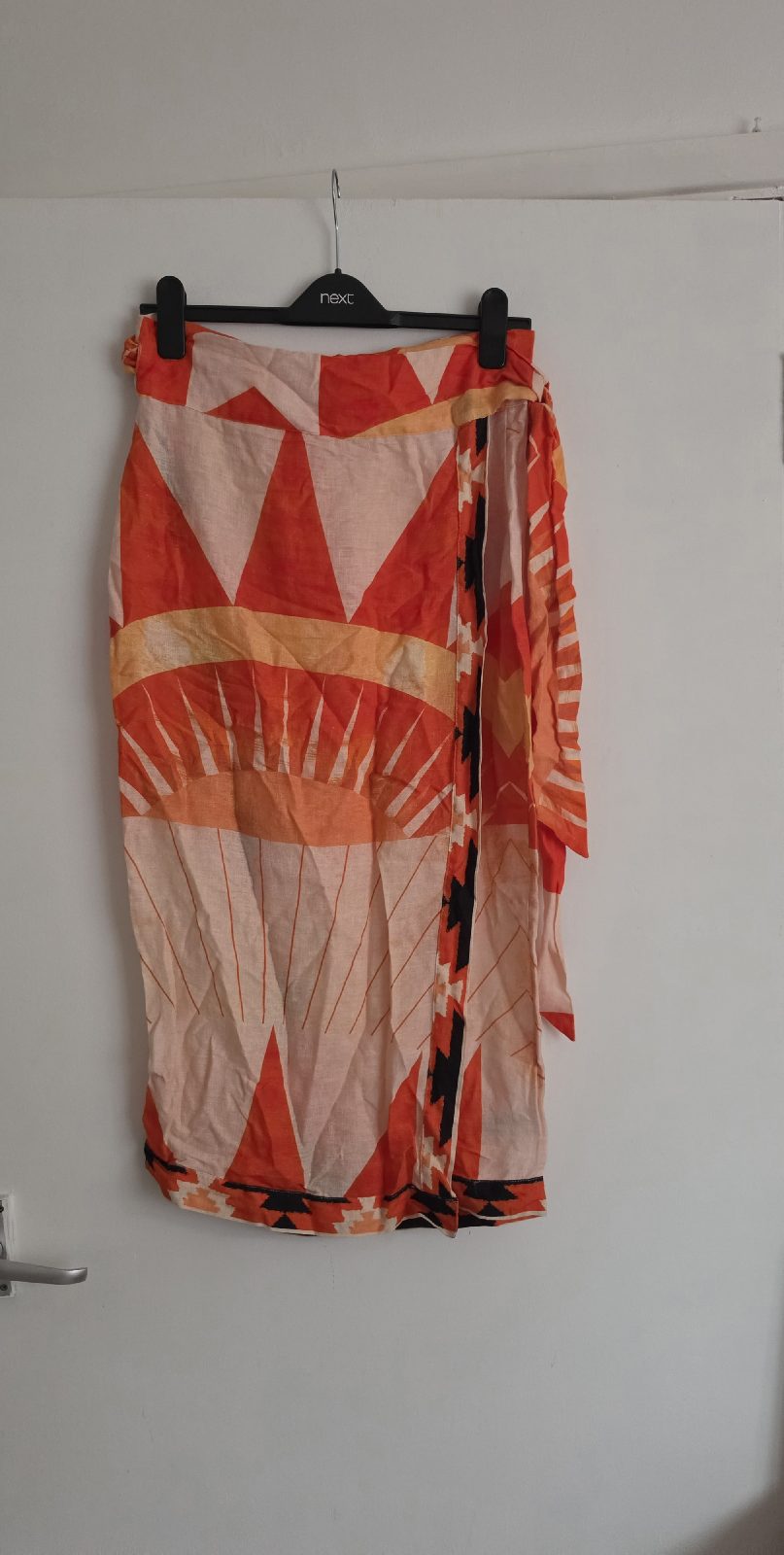 Linen-blend skirt featuring sun motifs and red and orange geometric patterns.