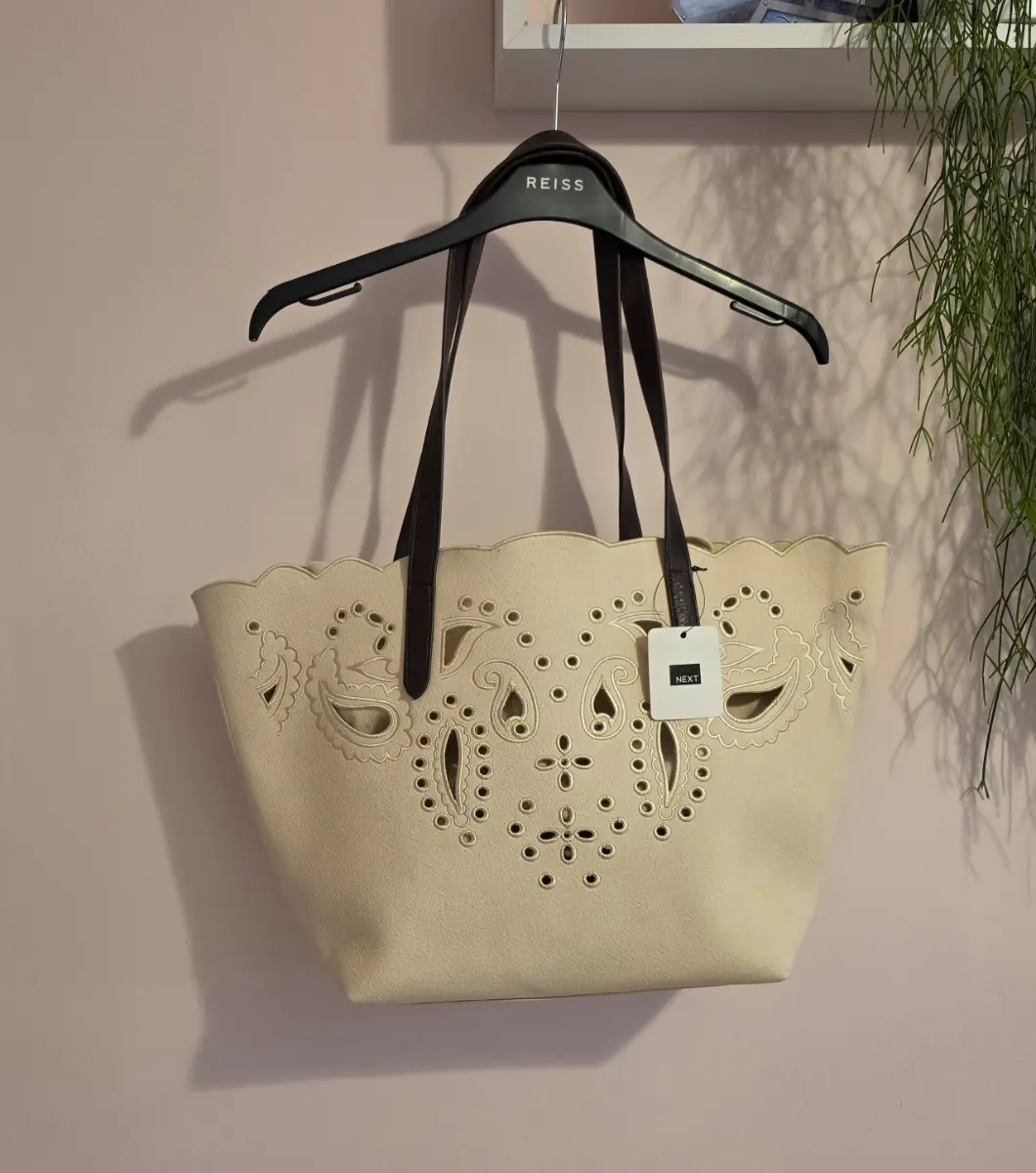 Floral cut-out shoulder bag with intricate lace-like cut-outs.